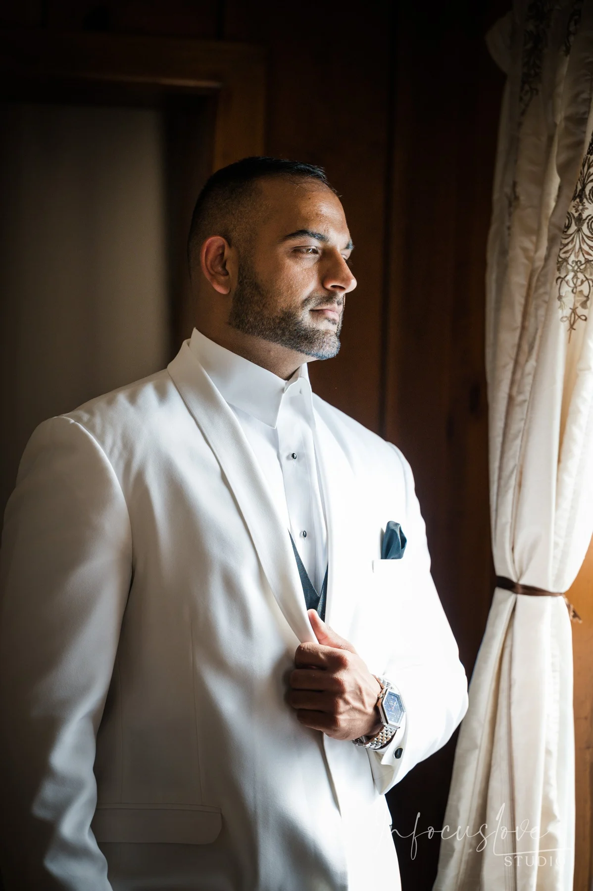 A groom getting ready beside a window