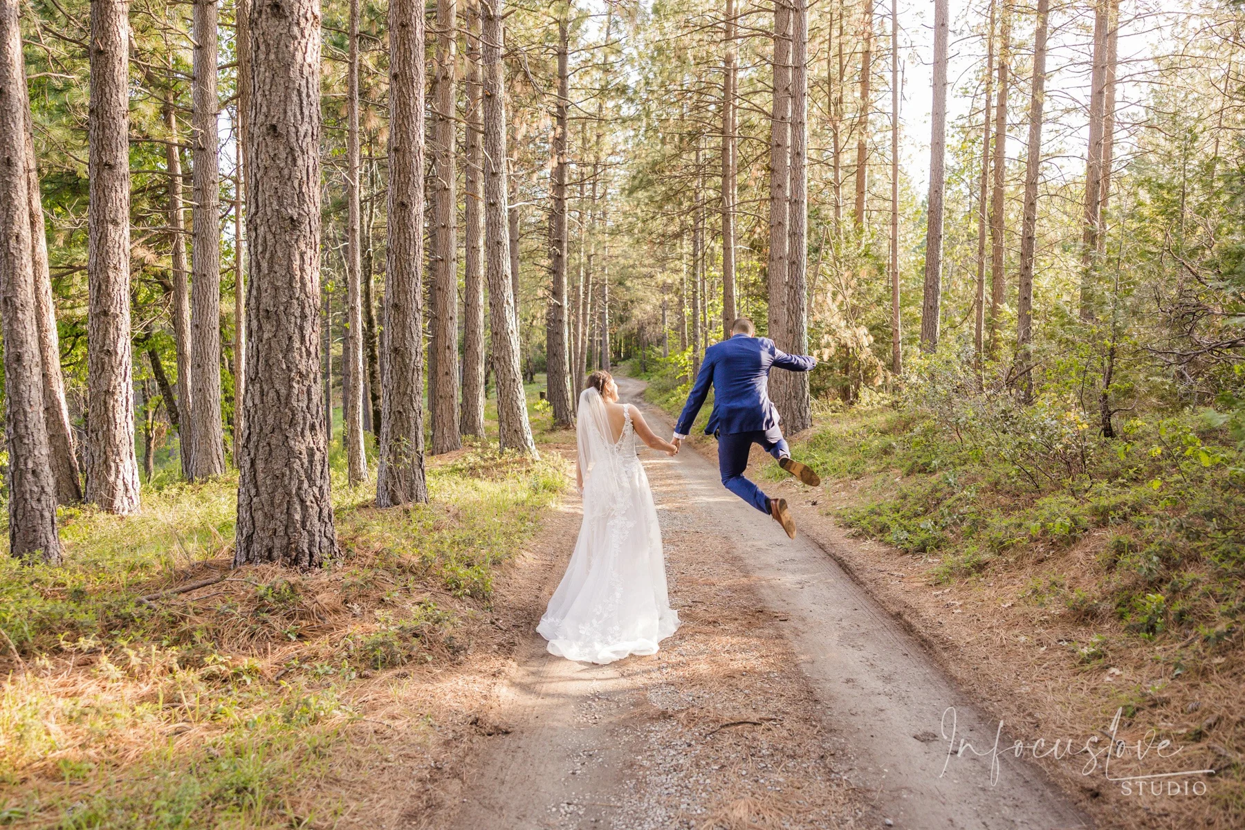 A wedding couple walking hand in hand along a forest path